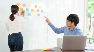 Toplantının iş ekibi çalışması ve ayna panosuna yapışkan bir yapışkan not. Ofis odasında ekiple beyin fırtınası planı toplamak için tartışıyorlar. 