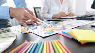 Grafik tasarımcı ekibi web tasarımı üzerinde çalışıyor. Tablet kullanarak renk örnekleri düzenleme ve yaratıcı ofiste çalışma masalarında bir stil kullanıyorlar..