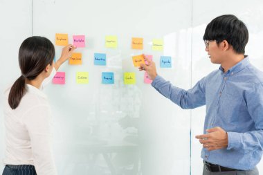 İşletme müdürü kendi takımı için fikir sunuyor ve cam pencere üzerine birçok not yapıştırıyor. İş görüşmeleri, yaratıcı ofis, planlama ve yönetim kavramında başarılı olmak için.