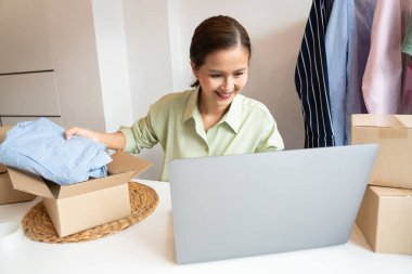 Asyalı işyeri sahibi, çevrimiçi dükkanının ambalaj kutusuyla çalışıyor. Müşterilere ürünleri dağıtmaya hazırlanıyor, alfa jenerasyonu yaşam tarzı konsepti.