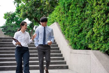 İş arkadaşları ofis binasının yakınında iş meselelerini tartışıyor, dışarıda birbirleriyle konuşuyorlar.