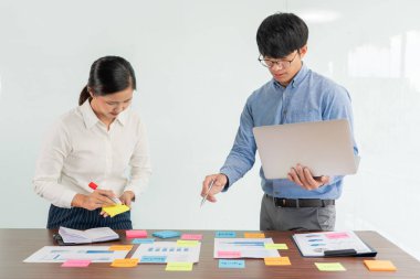 Beyin fırtınası yapan yaratıcı iş adamları grubu, iş konferansı odasında plan geliştirmek için konsept seçme konusunda fikir paylaşmak için yapışkan notlar seçiyor.