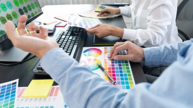 Grafik tasarımcı ekibi web tasarımı üzerinde çalışıyor. Tablet kullanarak renk örnekleri düzenleme ve yaratıcı ofiste çalışma masalarında bir stil kullanıyorlar..