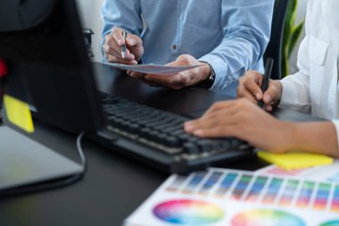 Grafik tasarımcı ekibi web tasarımı üzerinde çalışıyor. Tablet kullanarak renk örnekleri düzenleme ve yaratıcı ofiste çalışma masalarında bir stil kullanıyorlar..