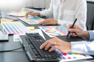 Grafik tasarımcı ekibi web tasarımı üzerinde çalışıyor. Tablet kullanarak renk örnekleri düzenleme ve yaratıcı ofiste çalışma masalarında bir stil kullanıyorlar..