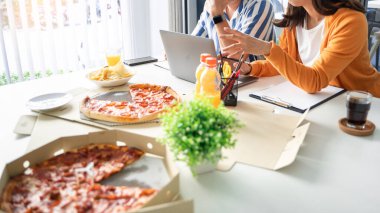 İş dünyası çalışanları iş hakkında tartışıyor ve öğle yemeği arasında yemek için pizza ve patates cipsi hazırlıyorlar.