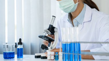 Laboratuvarda beyaz önlükle araştırma yapan bilim adamları eldivenleri analiz ediyor, test tüpleri örneklerine bakıyor, biyoteknoloji kavramına bakıyor.