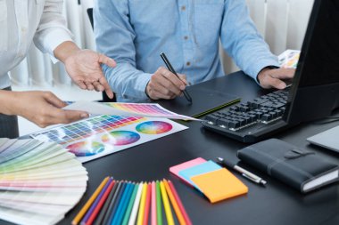 Grafik tasarımcı ekibi web tasarımı üzerinde çalışıyor. Tablet kullanarak renk örnekleri düzenleme ve yaratıcı ofiste çalışma masalarında bir stil kullanıyorlar..