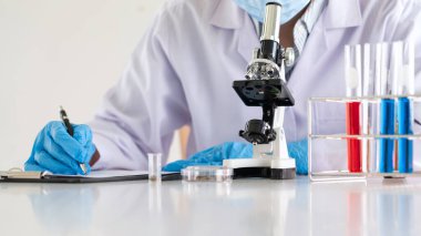 Laboratuvarda beyaz önlükle araştırma yapan bilim adamları eldivenleri analiz ediyor, test tüpleri örneklerine bakıyor, biyoteknoloji kavramına bakıyor..