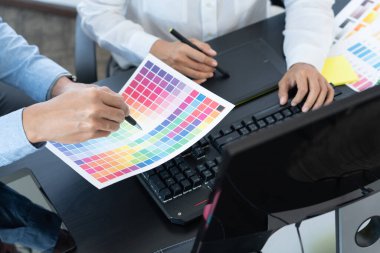 Grafik tasarımcı ekibi web tasarımı üzerinde çalışıyor. Tablet kullanarak renk örnekleri düzenleme ve yaratıcı ofiste çalışma masalarında bir stil kullanıyorlar..