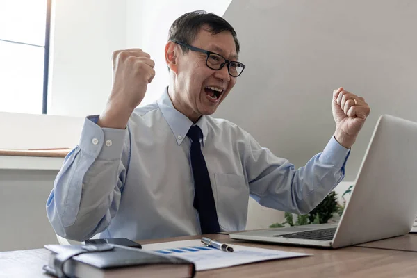 Senior handsome businessman happy and excited doing winner gesture with arms raised after Complete task of project, Cheerful positive excited careless peaceful