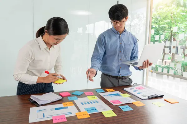 Beyin fırtınası yapan yaratıcı iş adamları grubu, iş konferansı odasında plan geliştirmek için konsept seçme konusunda fikir paylaşmak için yapışkan notlar seçiyor.