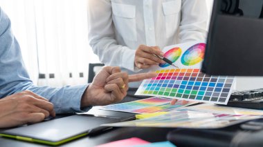 Grafik tasarımcı ekibi web tasarımı üzerinde çalışıyor. Tablet kullanarak renk örnekleri düzenleme ve yaratıcı ofiste çalışma masalarında bir stil kullanıyorlar..