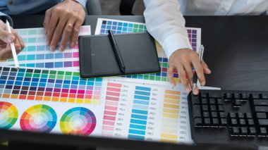 Grafik tasarımcı ekibi web tasarımı üzerinde çalışıyor. Tablet kullanarak renk örnekleri düzenleme ve yaratıcı ofiste çalışma masalarında bir stil kullanıyorlar..