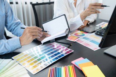 Grafik tasarımcı ekibi web tasarımı üzerinde çalışıyor. Tablet kullanarak renk örnekleri düzenleme ve yaratıcı ofiste çalışma masalarında bir stil kullanıyorlar..