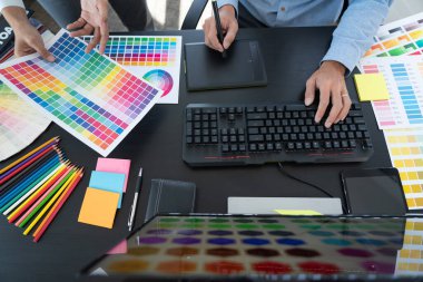 Grafik tasarımcı ekibi web tasarımı üzerinde çalışıyor. Tablet kullanarak renk örnekleri düzenleme ve yaratıcı ofiste çalışma masalarında bir stil kullanıyorlar..
