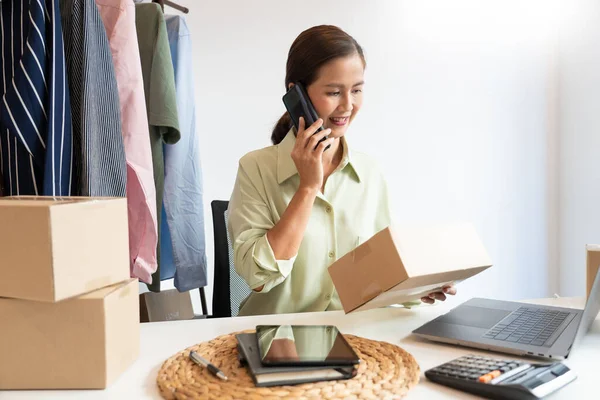 Asyalı işyeri sahibi, çevrimiçi dükkanının ambalaj kutusuyla çalışıyor. Müşterilere ürünleri dağıtmaya hazırlanıyor, alfa jenerasyonu yaşam tarzı konsepti.