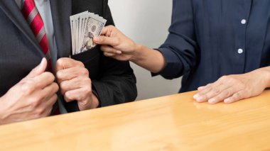 Amerika Birleşik Devletleri dolarlarını yolsuzluğa çeviren bir iş adamı çalışma masasındaki ortağından rüşvet konsepti.