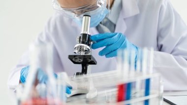 Laboratuvarda beyaz önlükle araştırma yapan bilim adamları eldivenleri analiz ediyor, test tüpleri örneklerine bakıyor, biyoteknoloji kavramına bakıyor..