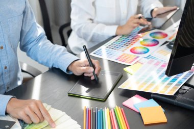Grafik tasarımcısı veya yaratıcı birlikte çalışarak grafik tableti ve çalışma arkadaşı ile çalışma masasında bir stil kullanarak renklendirme