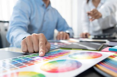 Grafik tasarımcı ekibi web tasarımı üzerinde çalışıyor. Tablet kullanarak renk örnekleri düzenleme ve yaratıcı ofiste çalışma masalarında bir stil kullanıyorlar..