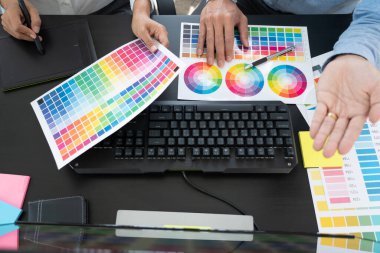 Grafik tasarımcı ekibi web tasarımı üzerinde çalışıyor. Tablet kullanarak renk örnekleri düzenleme ve yaratıcı ofiste çalışma masalarında bir stil kullanıyorlar..