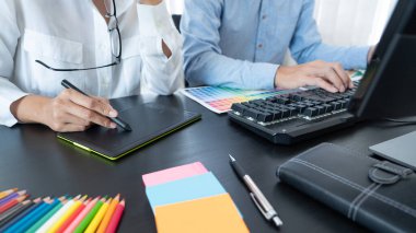 Grafik tasarımcı ekibi web tasarımı üzerinde çalışıyor. Tablet kullanarak renk örnekleri düzenleme ve yaratıcı ofiste çalışma masalarında bir stil kullanıyorlar..