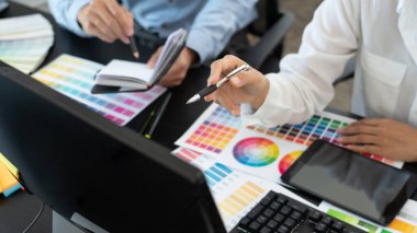 Grafik tasarımcı ekibi web tasarımı üzerinde çalışıyor. Tablet kullanarak renk örnekleri düzenleme ve yaratıcı ofiste çalışma masalarında bir stil kullanıyorlar..