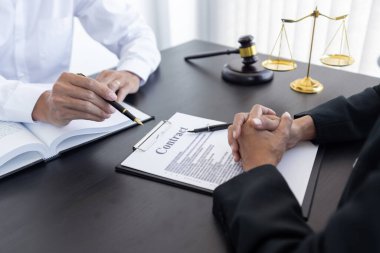 Hukuk, terazi ve çekiç masaya yatırıldı. İki avukat sözleşme kağıtları ve hukuk konularında tartışıyor..