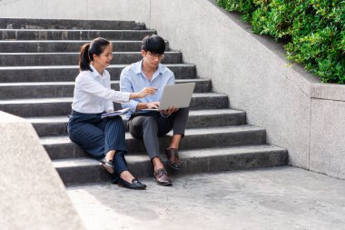 İş arkadaşları ofis binasının yakınında iş meselelerini tartışıyor, dışarıda birbirleriyle konuşuyorlar.