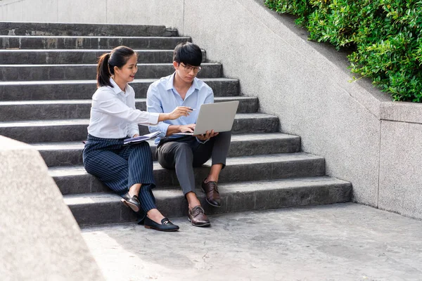 İş arkadaşları ofis binasının yakınında iş meselelerini tartışıyor, dışarıda birbirleriyle konuşuyorlar.