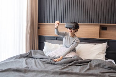 Ev konseptinden çalış. Gri kazaklı, görsel simülatör cihazı takan bir kadın..