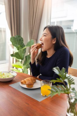 Evinde salata yedikten sonra tatlı olarak portakal suyu yiyen genç bir kadının yemek konsepti..