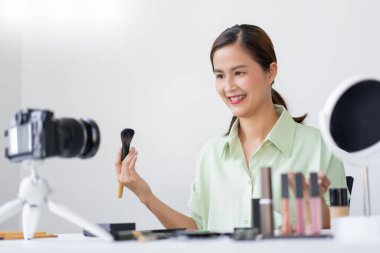 Makyaj fırçası kullanarak yanağına pudra sürten bir güzellik uzmanı..