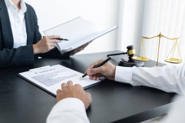 Hukuk, terazi ve çekiç masada. İki adam anlaşma yapıyor ve imzalıyor. Hukuk konuları belirleniyor..