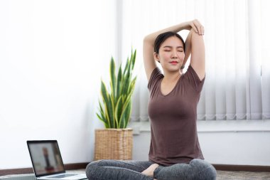 Huzurlu bir oturma odasında yoga yapmak için konsantre olan sakin bir kadın..