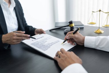 Hukuk, terazi ve çekiç masada. İki adam anlaşma yapıyor ve imzalıyor. Hukuk konuları belirleniyor..