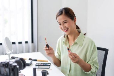 Kendine güvenen bir güzellik blogcusu ürünün kalitesini belirten pembe sıvı ruj gösteriyor..