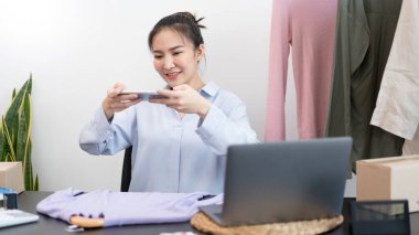 Canlı alışveriş konsepti. İnternetten bir kadın satıcının online dükkanında bir ürün olan kumaşın fotoğrafını çekmesi..