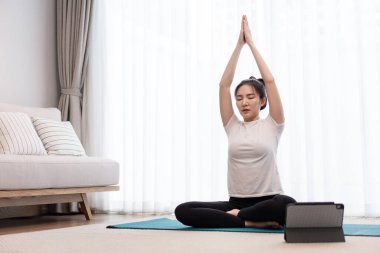 Üretken aktivite kavramı. Genç bir kadın gözlerini kapatıyor. Sessiz odadaki yeşil paspasın üzerinde ellerini birleştiriyor..