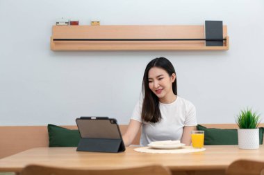 Oturma odası konsepti. Bir kadın elektronik cihazını kahve dükkanının rahat odasında uzaktan çalışmak için kullanıyor..