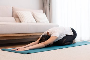 Oturma odasında, yeşil yoga minderinin üzerinde vücudunu paralel eğen bir kızın verimlilik kavramı..