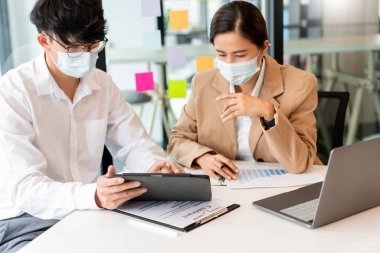 İki iş arkadaşı, hijyenik koruma altında imzayı atmadan önce sözleşmeyi gözden geçirmek için birbirlerine yardım ediyorlar..