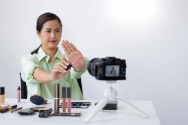 Kendine güvenen bir güzellik blogcusu ürünün kalitesini belirten pembe sıvı ruj gösteriyor..