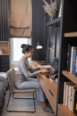 Ev konseptinden çalış. Ekşi saçlı genç bir kız yatak odasında uzaktan kumandayla çalışıyor.. 