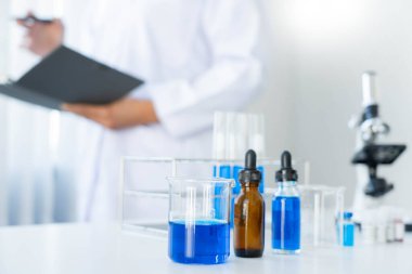 Laboratuvarda beyaz önlükle araştırma yapan bilim adamları eldivenleri analiz ediyor, test tüpleri örneklerine bakıyor, biyoteknoloji kavramına bakıyor..