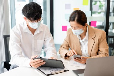 İki iş arkadaşı, hijyenik koruma altında imzayı atmadan önce sözleşmeyi gözden geçirmek için birbirlerine yardım ediyorlar..