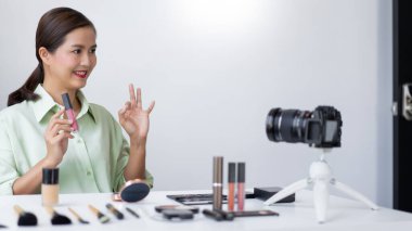 Kendine güvenen bir güzellik blogcusu ürünün kalitesini belirten pembe sıvı ruj gösteriyor..