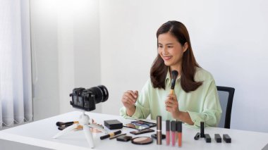 Makyaj fırçası kullanarak yanağına pudra sürten bir güzellik uzmanı..