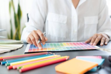 Grafik tasarımcı ekibi web tasarımı üzerinde çalışıyor. Tablet kullanarak renk örnekleri düzenleme ve yaratıcı ofiste çalışma masalarında bir stil kullanıyorlar..